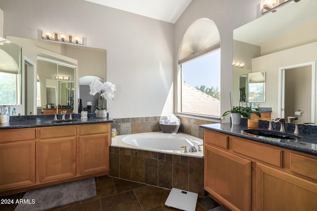 bathroom with tile patterned flooring, vanity, and a relaxing tiled tub