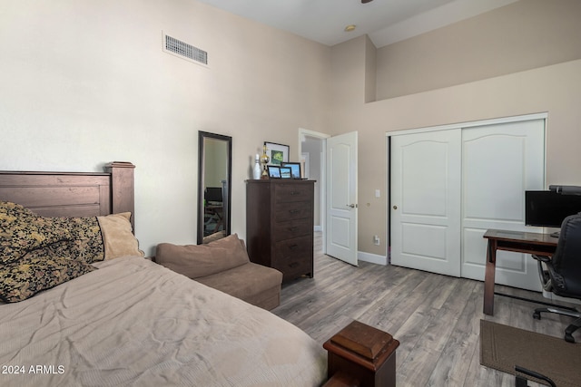 bedroom featuring a high ceiling, light hardwood / wood-style flooring, and a closet