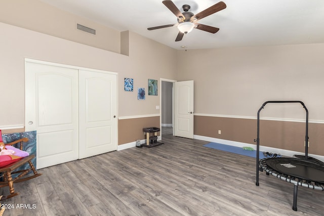 workout area featuring ceiling fan, vaulted ceiling, and hardwood / wood-style flooring