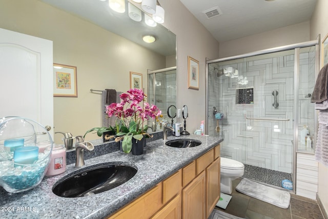 bathroom featuring tile patterned flooring, vanity, a shower with shower door, and toilet