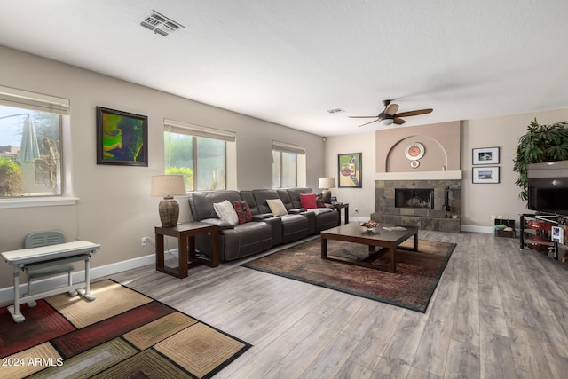 living room with ceiling fan, a tile fireplace, and light hardwood / wood-style flooring