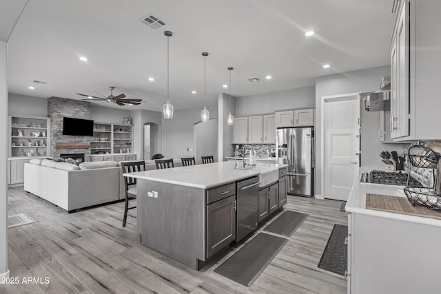 kitchen with visible vents, arched walkways, a sink, stainless steel appliances, and a kitchen bar