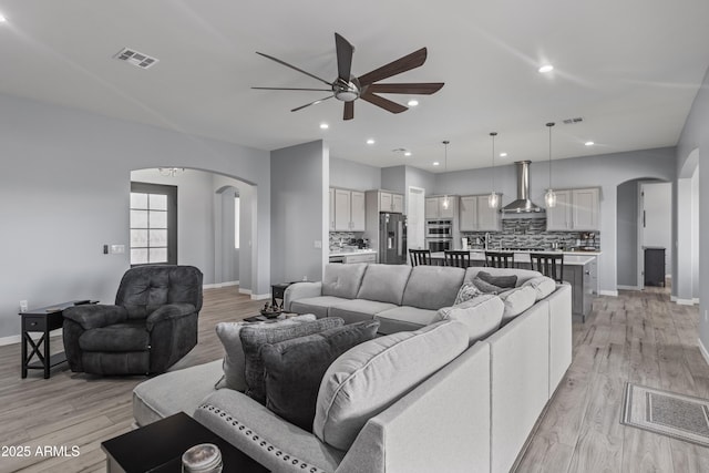 living area with arched walkways, visible vents, and light wood-style flooring