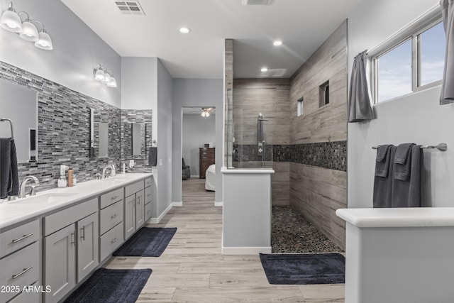 bathroom featuring visible vents, a walk in shower, a sink, double vanity, and decorative backsplash