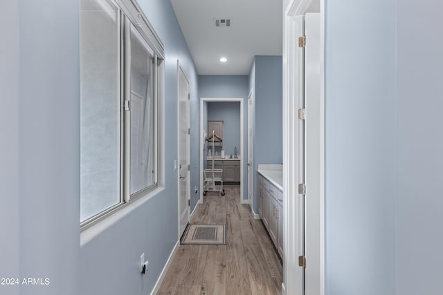 hallway with light wood finished floors, visible vents, recessed lighting, and baseboards