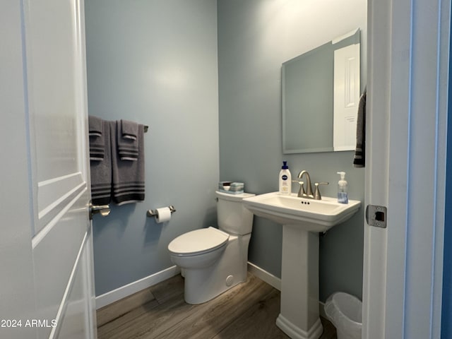 half bathroom featuring toilet, wood finished floors, and baseboards