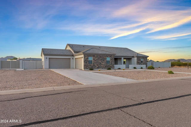 view of front of house featuring fence, driveway, stone siding, an attached garage, and a gate