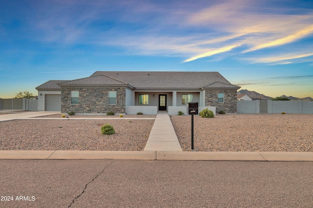 view of front facade featuring cooling unit, fence, concrete driveway, a garage, and stone siding