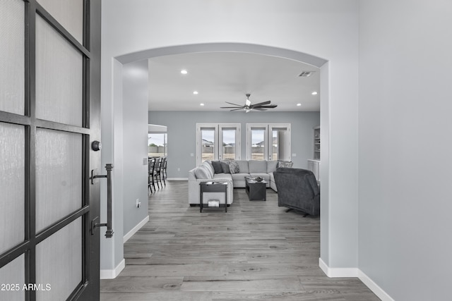 foyer entrance with visible vents, baseboards, light wood-style flooring, recessed lighting, and arched walkways