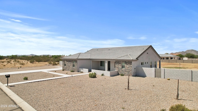 view of front of house featuring a tile roof, fence private yard, stone siding, and stucco siding