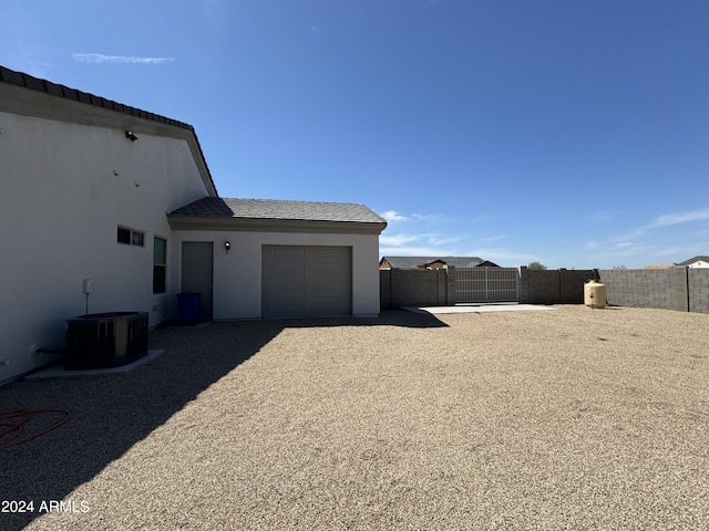 view of yard featuring a gate, central air condition unit, an attached garage, and fence