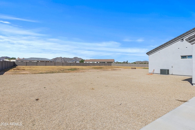 view of yard with a mountain view, central AC, and fence