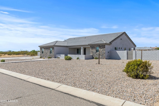 view of front of house with fence, stone siding, and stucco siding