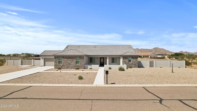 view of front of property with a tiled roof, stone siding, concrete driveway, and fence