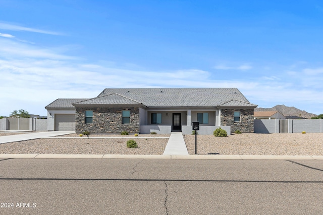 view of front of home with stone siding, an attached garage, concrete driveway, and fence