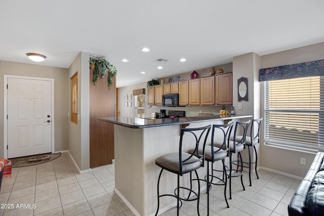 kitchen featuring light tile patterned floors, a kitchen bar, and kitchen peninsula