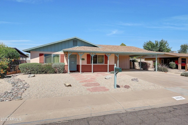 ranch-style home featuring a carport, covered porch, brick siding, driveway, and fence