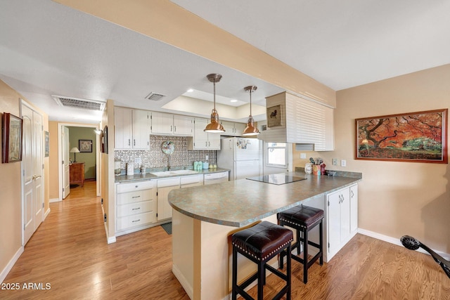 kitchen featuring white appliances, a peninsula, light wood-style flooring, and baseboards