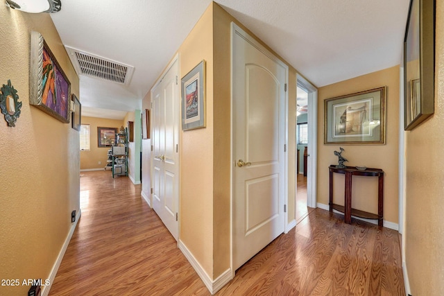 hallway with light wood-type flooring and baseboards