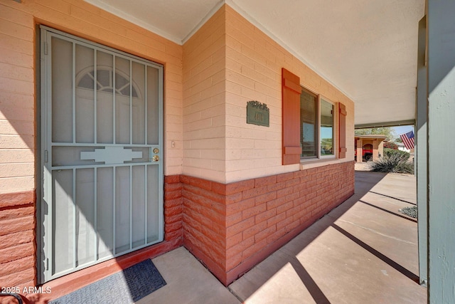 property entrance with covered porch and brick siding