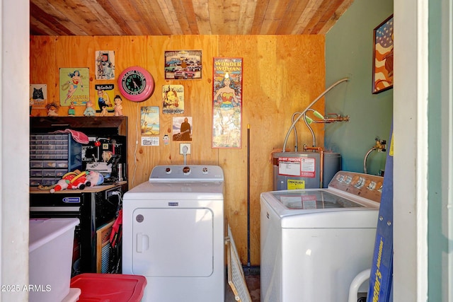 laundry room with wooden ceiling, water heater, washing machine and dryer, and wooden walls