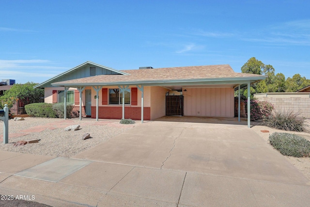 ranch-style house with board and batten siding, concrete driveway, roof with shingles, and fence