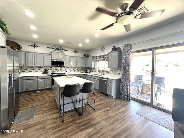 kitchen featuring decorative backsplash, a kitchen island, appliances with stainless steel finishes, gray cabinetry, and recessed lighting