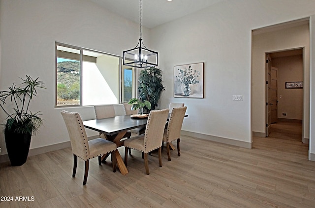 dining space featuring vaulted ceiling, light wood-type flooring, and an inviting chandelier