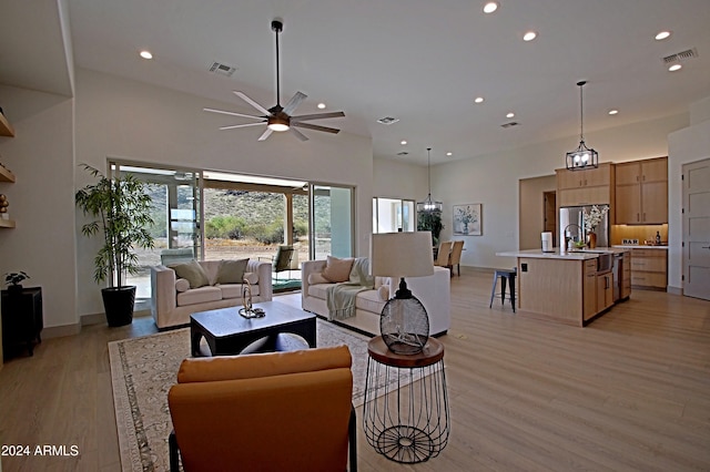 living room featuring a high ceiling, light hardwood / wood-style flooring, and ceiling fan