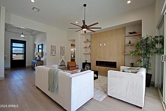 living room featuring a tiled fireplace, light hardwood / wood-style floors, and ceiling fan