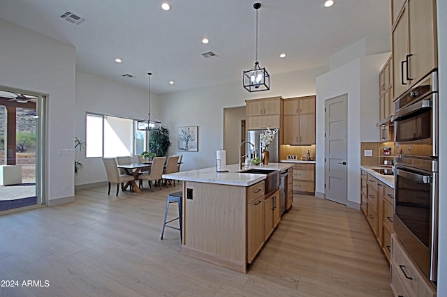 kitchen featuring appliances with stainless steel finishes, sink, an island with sink, and hanging light fixtures