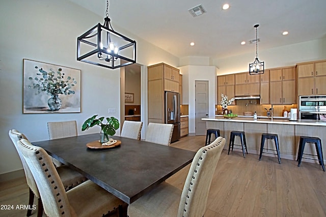 dining space with light hardwood / wood-style floors and a notable chandelier