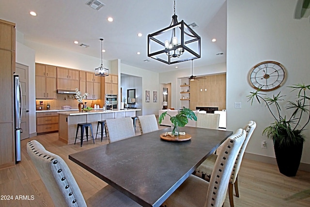 dining area featuring ceiling fan with notable chandelier and light wood-type flooring