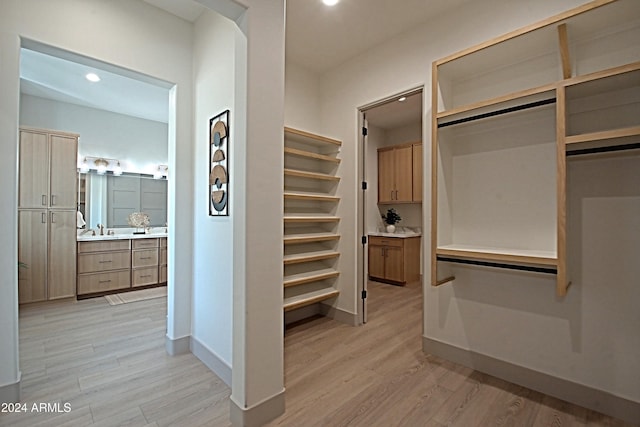 spacious closet with light hardwood / wood-style floors and sink