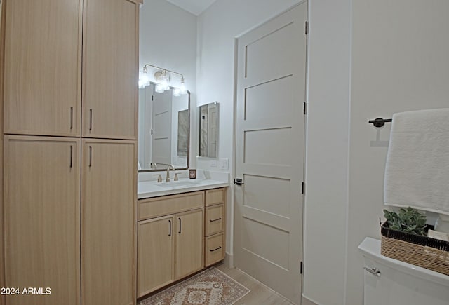 bathroom with vanity, toilet, and hardwood / wood-style flooring