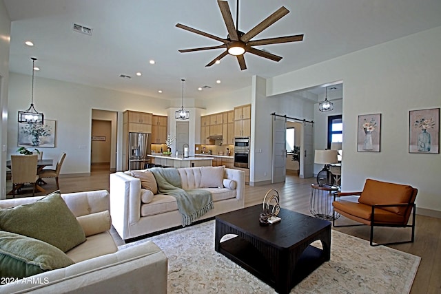 living room featuring a barn door, dark hardwood / wood-style floors, and ceiling fan