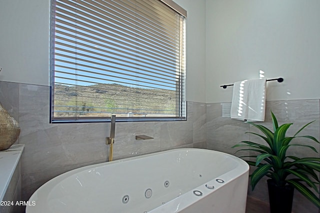 bathroom with a tub and tile walls