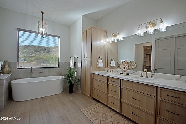 bathroom with hardwood / wood-style floors, tile walls, a bathing tub, vanity, and an inviting chandelier