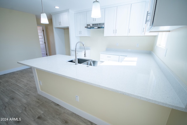 kitchen featuring pendant lighting, light stone countertops, sink, white cabinets, and kitchen peninsula