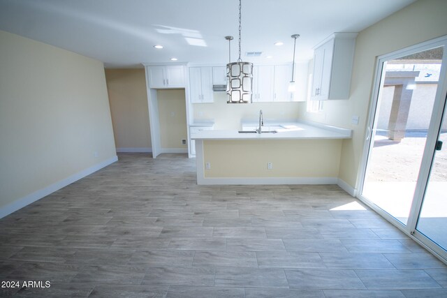 kitchen featuring white cabinets, kitchen peninsula, sink, and pendant lighting