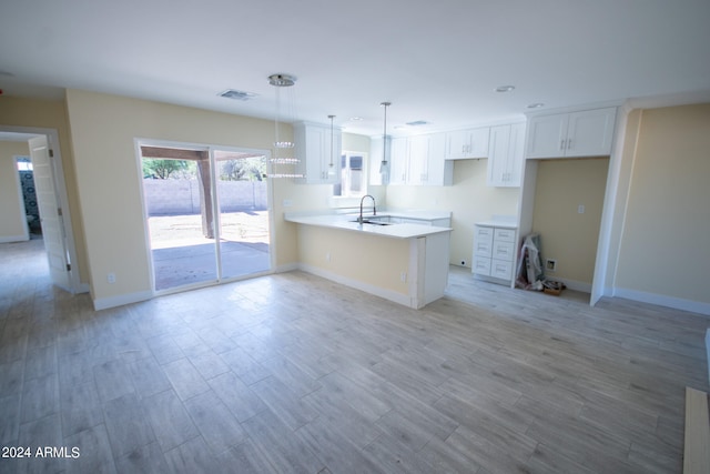 kitchen featuring light hardwood / wood-style floors, white cabinetry, pendant lighting, and kitchen peninsula