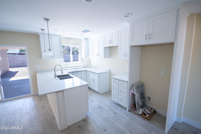 kitchen featuring white cabinets, a wealth of natural light, sink, and decorative light fixtures