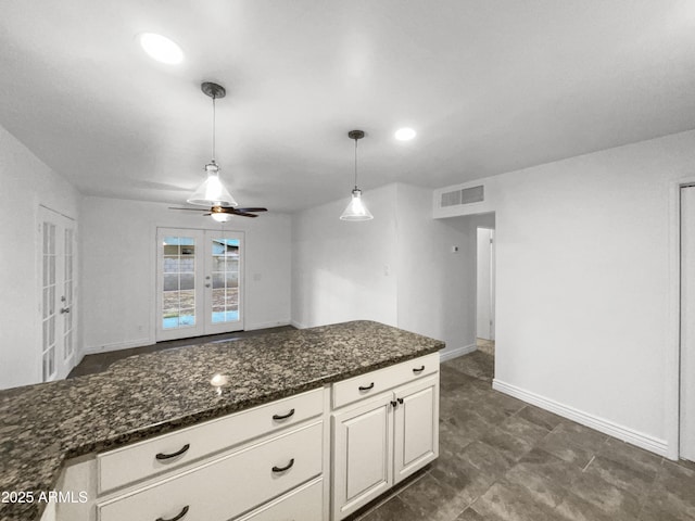 kitchen with visible vents, a ceiling fan, dark stone countertops, french doors, and hanging light fixtures