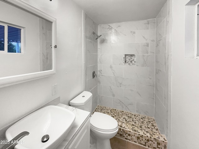 bathroom featuring tiled shower, toilet, and vanity