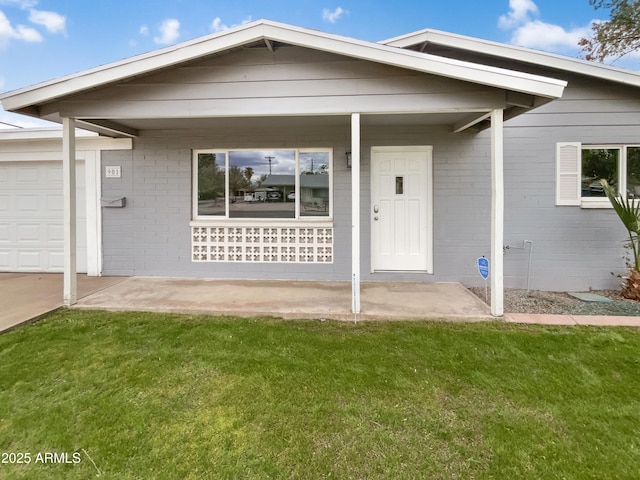 property entrance featuring brick siding, covered porch, an attached garage, and a yard