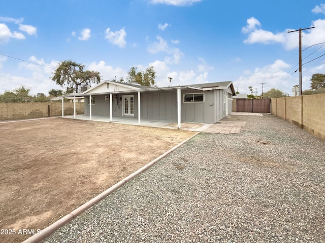 back of property featuring driveway, a fenced backyard, french doors, a patio area, and board and batten siding