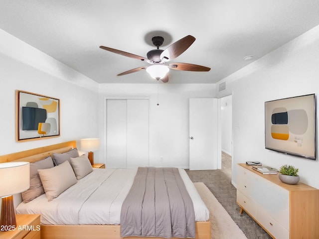 bedroom featuring carpet flooring, a ceiling fan, visible vents, and a closet