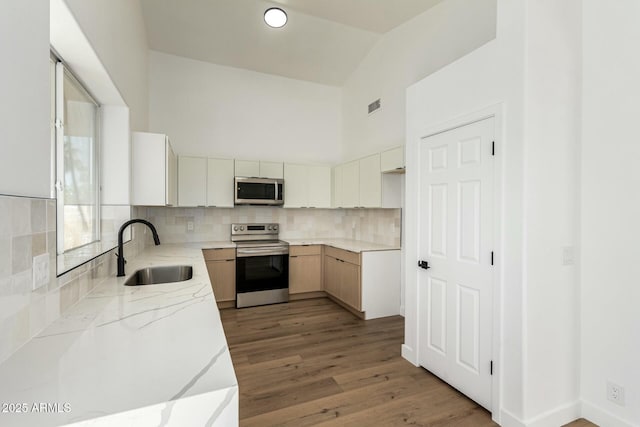 kitchen featuring visible vents, light wood-style flooring, light stone counters, stainless steel appliances, and a sink