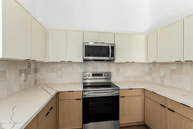 kitchen featuring a towering ceiling, light stone countertops, stainless steel appliances, and backsplash