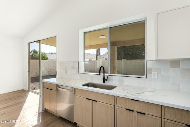 kitchen with lofted ceiling, light wood-type flooring, a healthy amount of sunlight, stainless steel dishwasher, and a sink